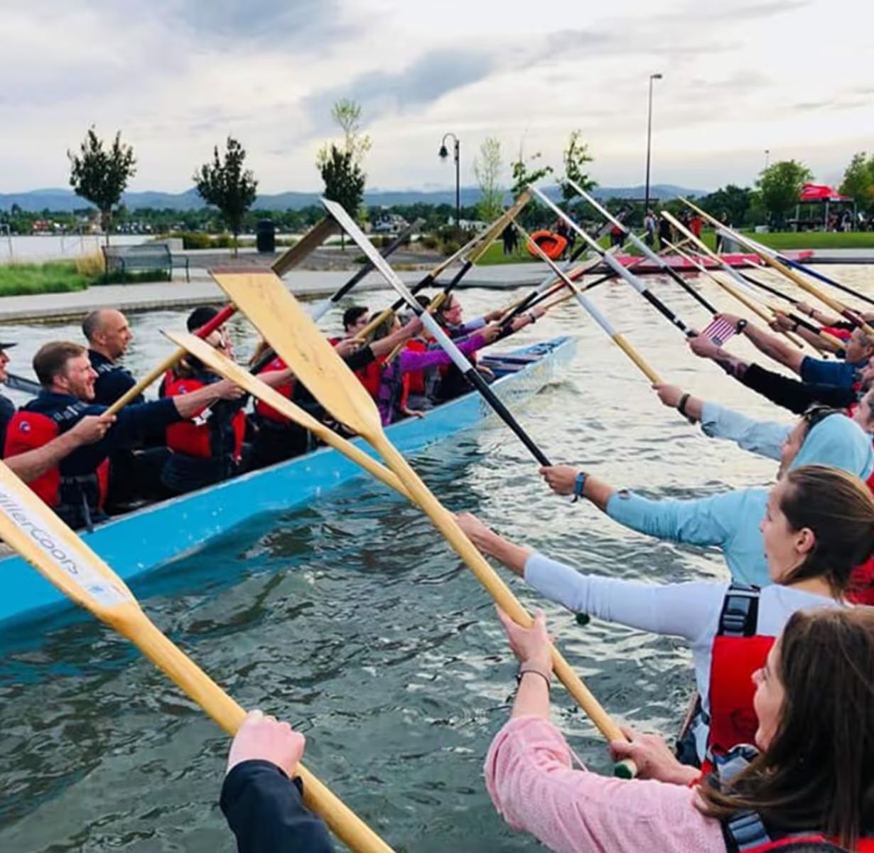 An Adaptive Adventures paddling programme, participants raising paddles from kayaks