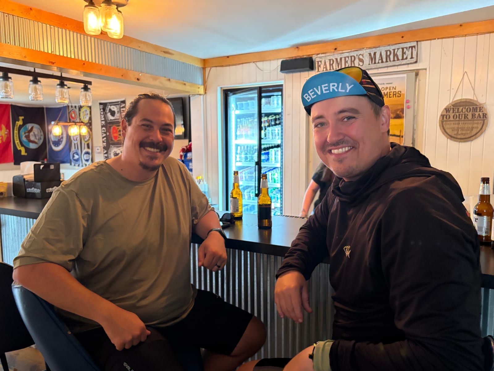 Two riders leaning on a bar counter in a small-town taproom