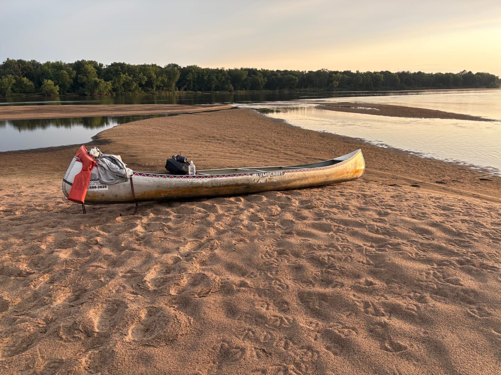 A single canoe pulled up on an empty sandbar as the light goes