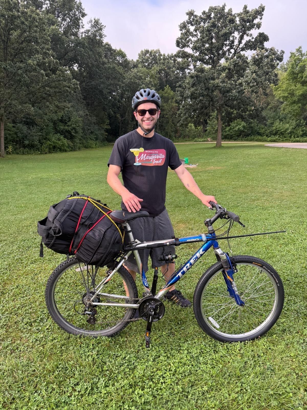 A rider standing beside a mountain bike loaded with a dry bag and camping gear