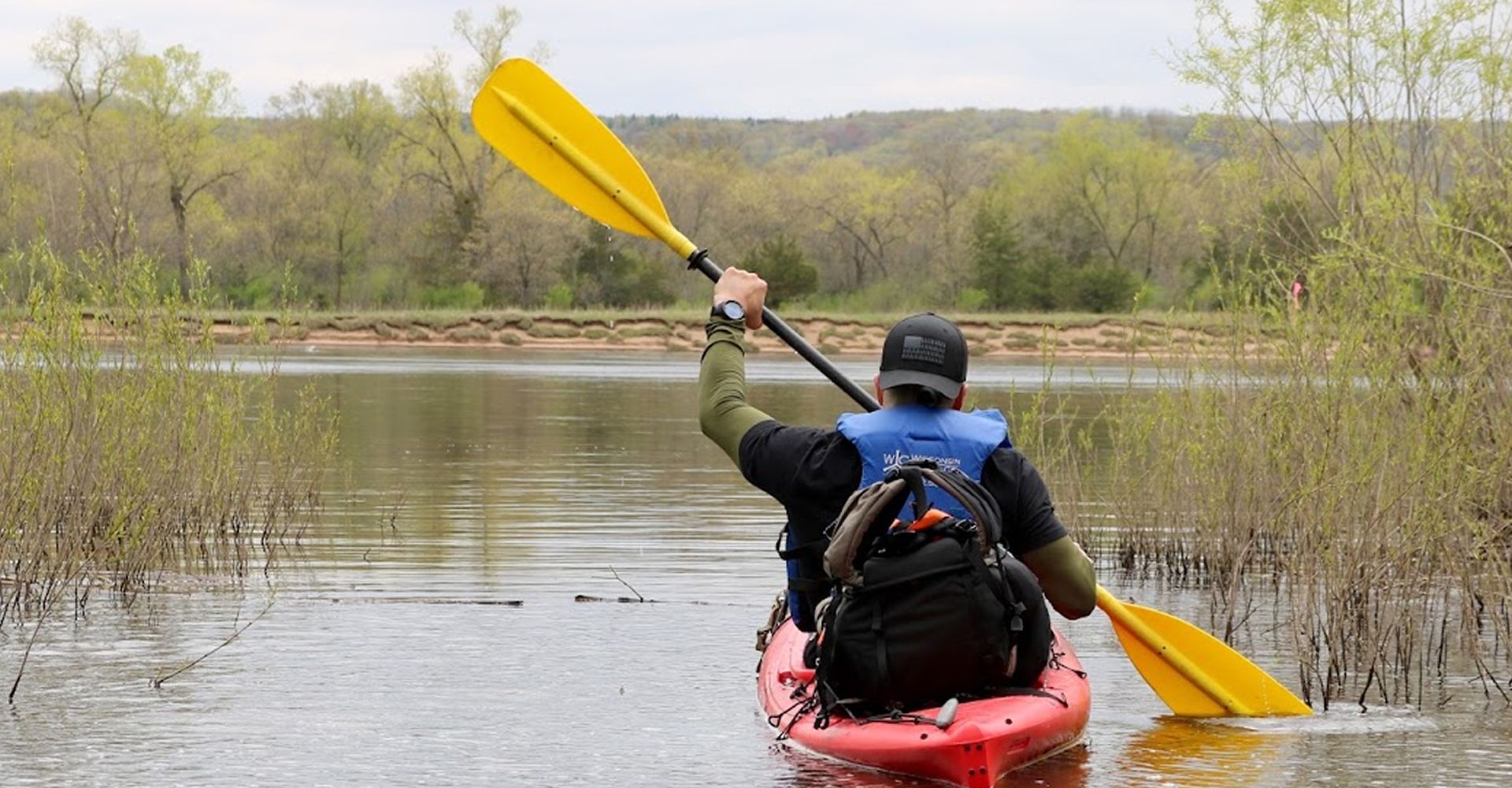 A paddler raising their paddle overhead in celebration on the river