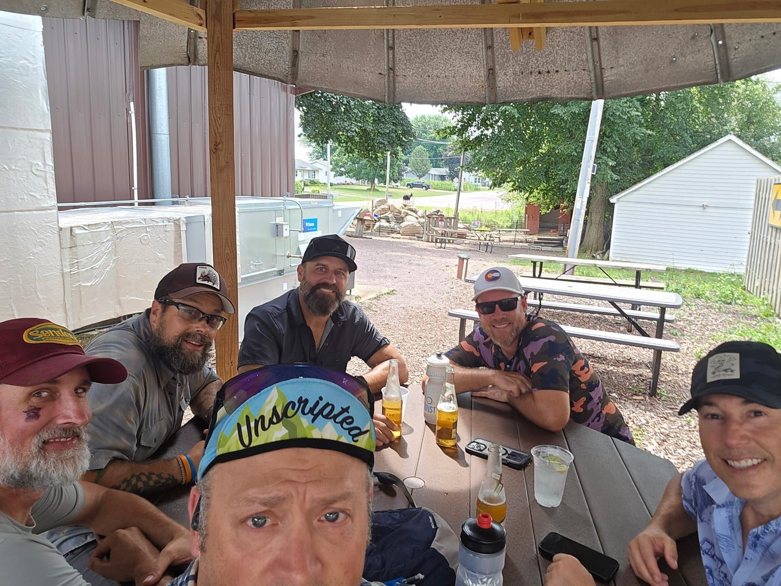A group of riders sitting round a picnic table under a shelter with drinks